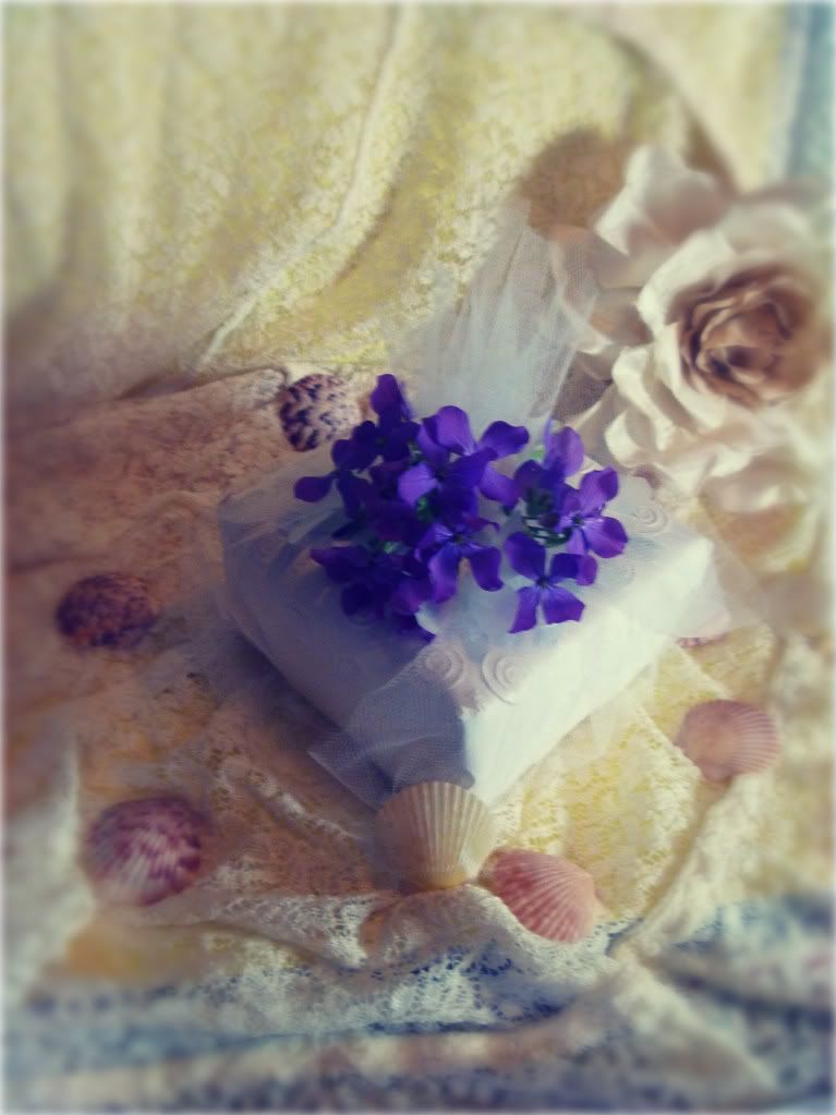 white tulle wrapped present with purple flowers antique lace sea shells