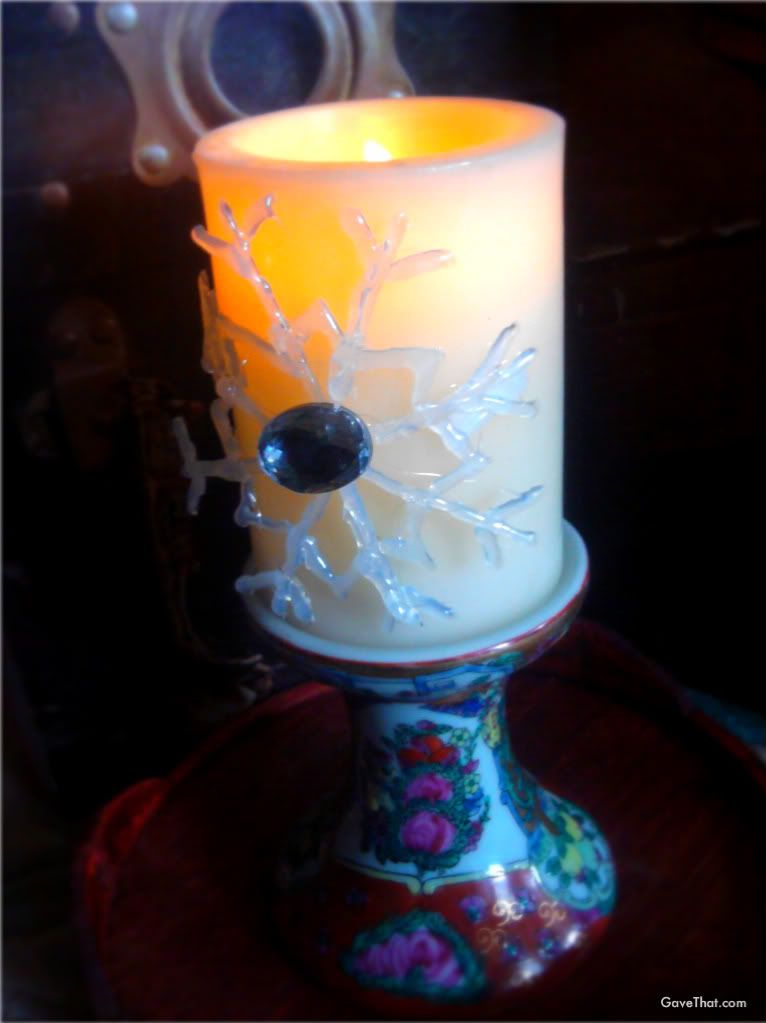 DIY hot glue gun snowflake ornaments adorning a candle