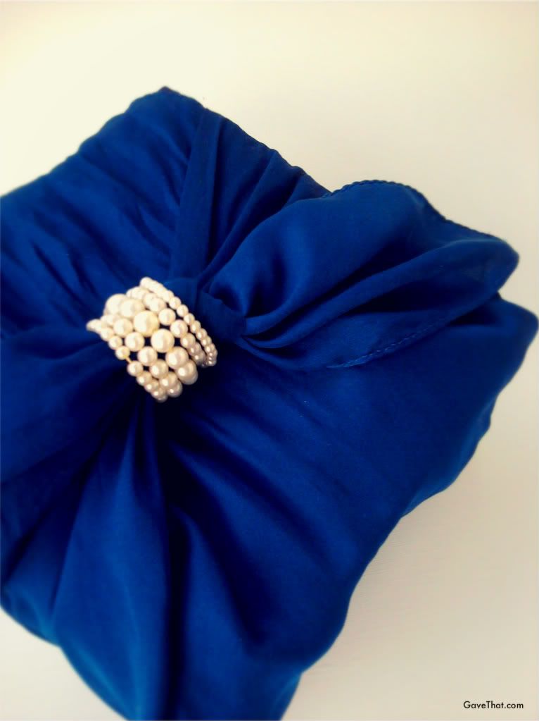 Furoshiki wrapped present using a silk scarf and vintage pearl necklace at the center knot by Marie of gave that blog