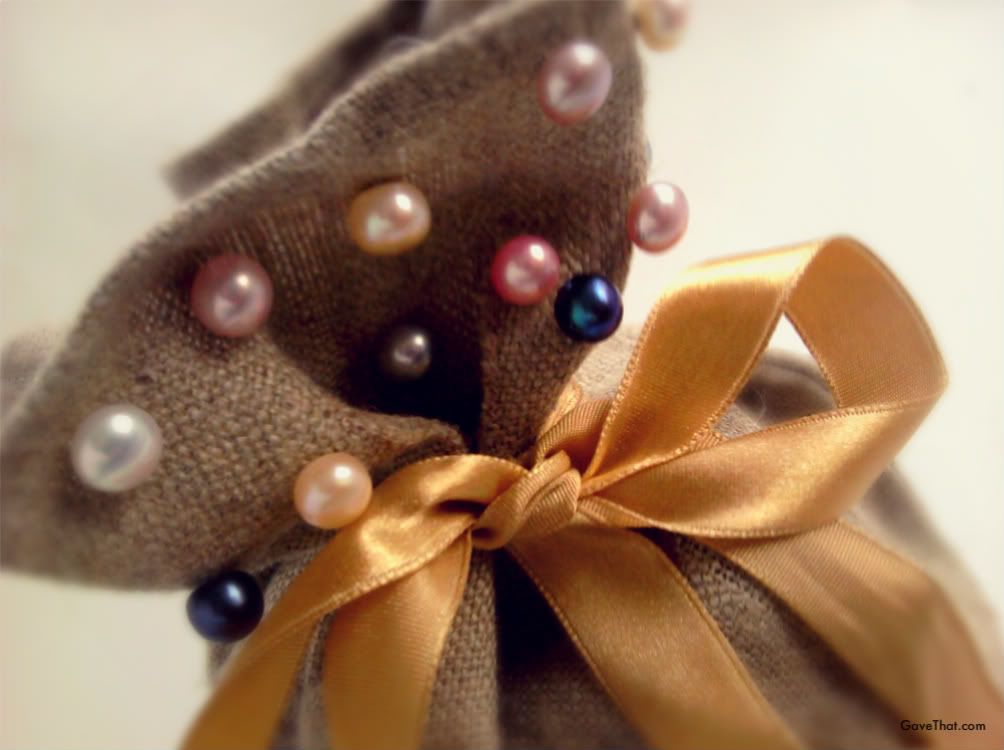 Pearl earrings adorn the top of a burlap gift bag