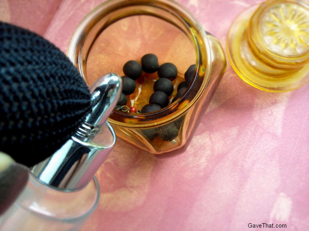 Placing wooden beaded bracelet in glass jar and misting with perfume